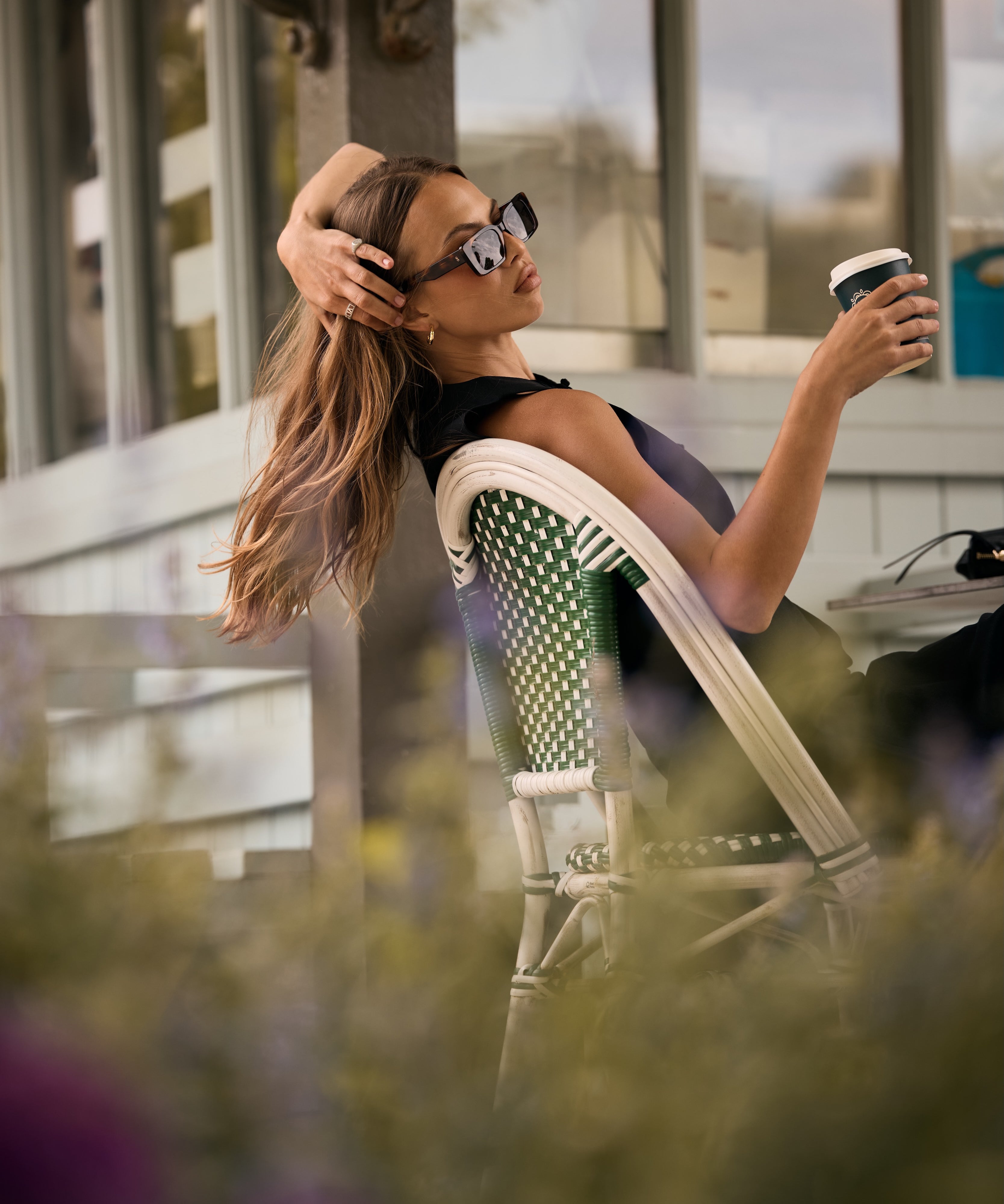 Woman sitting outdoors, holding a coffee cup, with blurred background